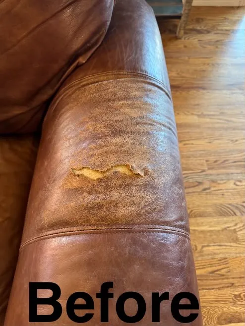 Brown leather sofa armrest with a torn, peeling patch and a worn, scuffed finish